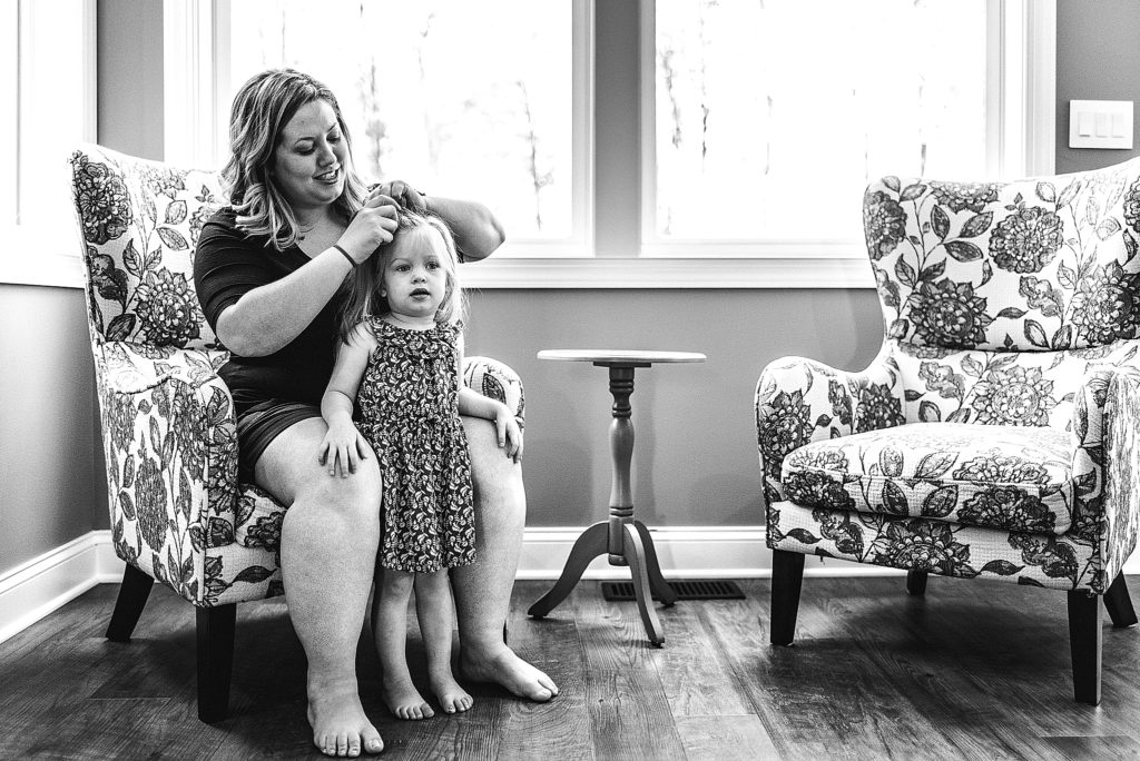 Charlotte Lifestyle Photographer also serving Mooresville Davidson Cornelius Huntersville specializes in family newborn branding natural fun moments mother daughter mom doing girl's hair black and white photography session