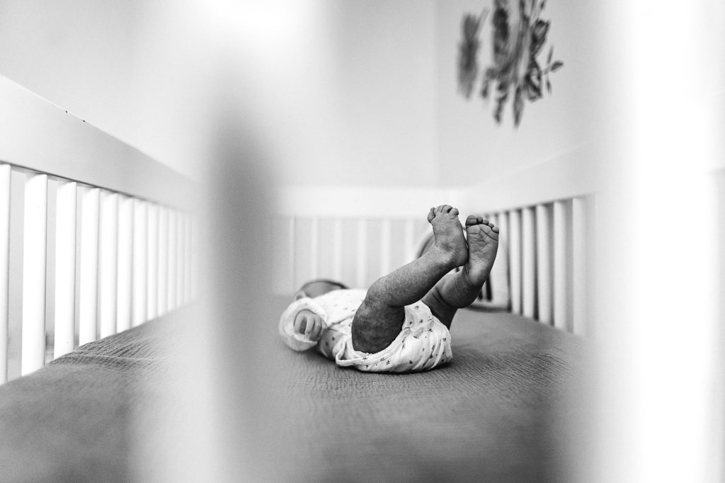 Charlotte Lifestyle Newborn Photography baby natural candid moment together Mooresville Photographer in crib baby feet black and white