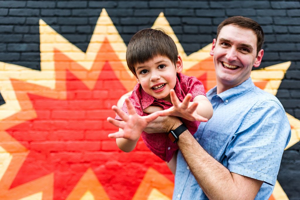 Charlotte Lifestyle Photographer also serving Mooresville Davidson Cornelius Huntersville specializes in family newborn branding natural fun moments family session father and son at colorful mural superman